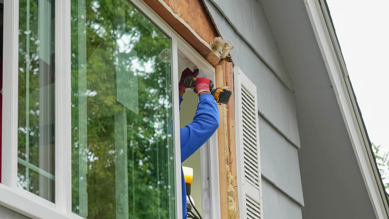 Crew installing new replacement windows on a residential home